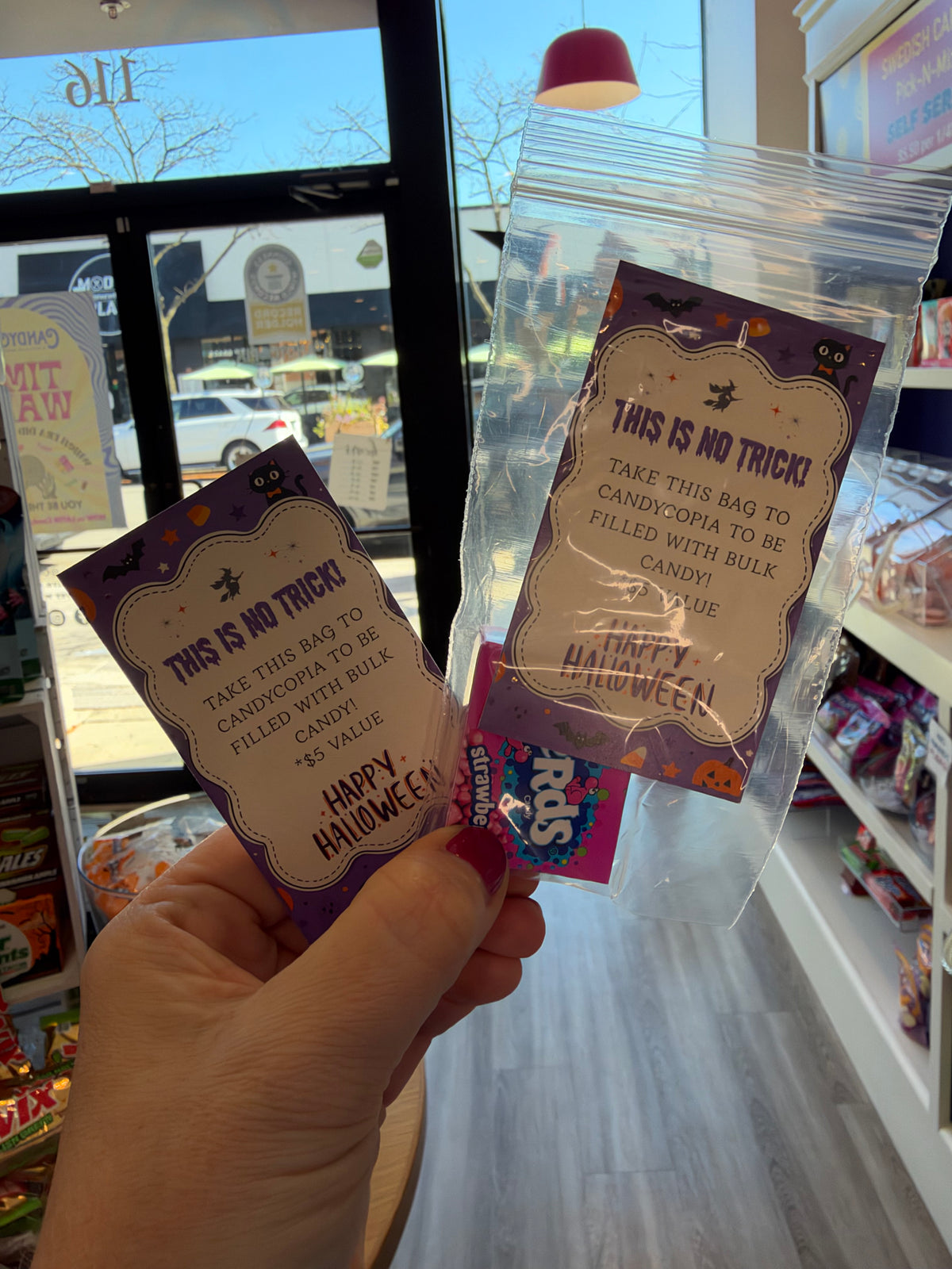 Front view of Halloween favor bags showcasing purple trick or treat designs and a clear candy pouch in a candy shop