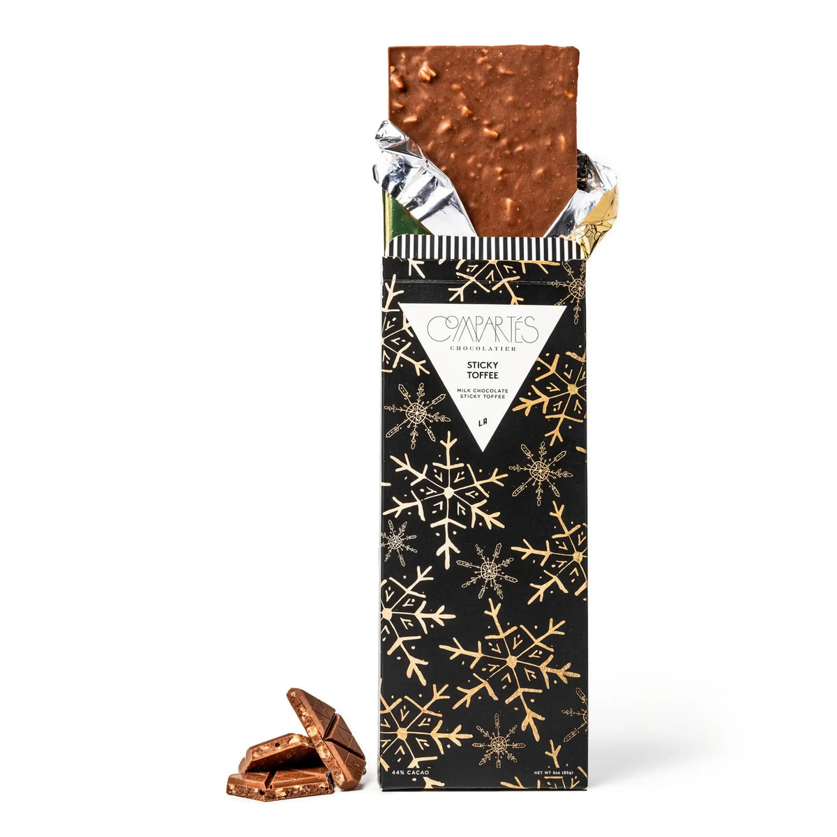 Front view of Compartes Sticky Toffee milk chocolate bar showcasing an opened wrapper and chocolate pieces on a white background
