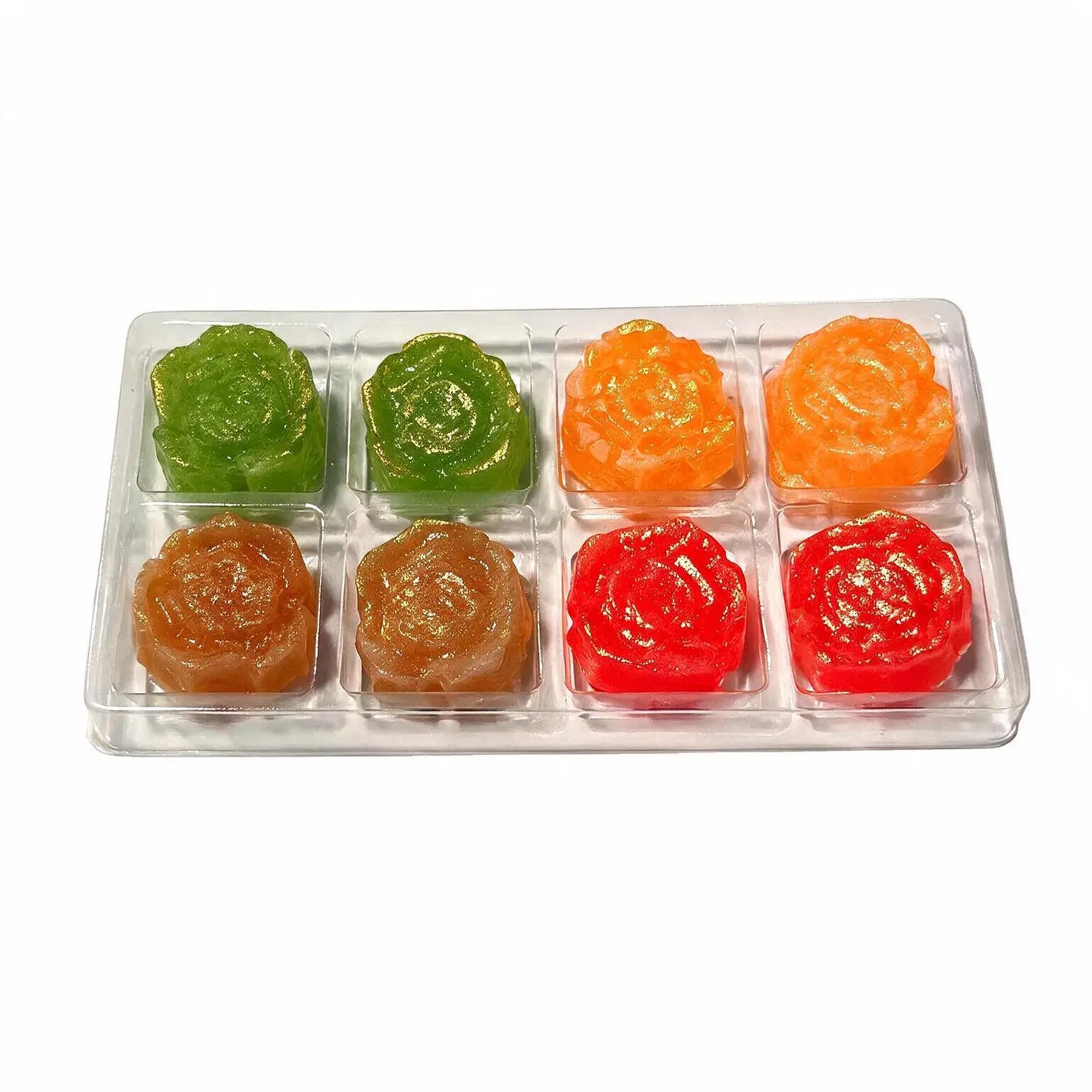A clear plastic tray holding six flower-shaped translucent candies or gelatin pieces in assorted colors: green, orange, brown, red, and pinkish-red, arranged in two rows of three on a white background