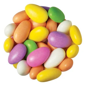 A pile of colorful, oblong candy-coated chocolates, also known as milk chocolate almonds, in pastel shades of yellow, purple, pink, green, orange, and white on a plain white background.
