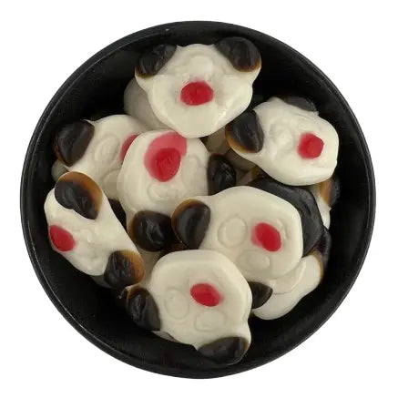 A top-down view of several panda-shaped gummy candies with white, black, and red coloring, arranged inside a round black bowl on a white background