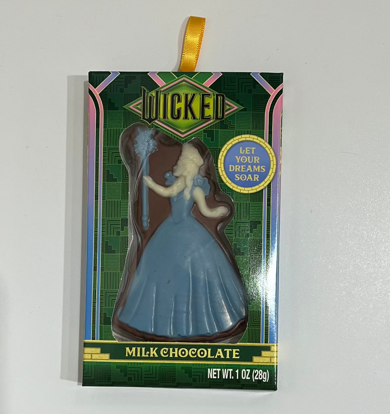 Card with a character in a blue dress on a white surface with scissors in the background