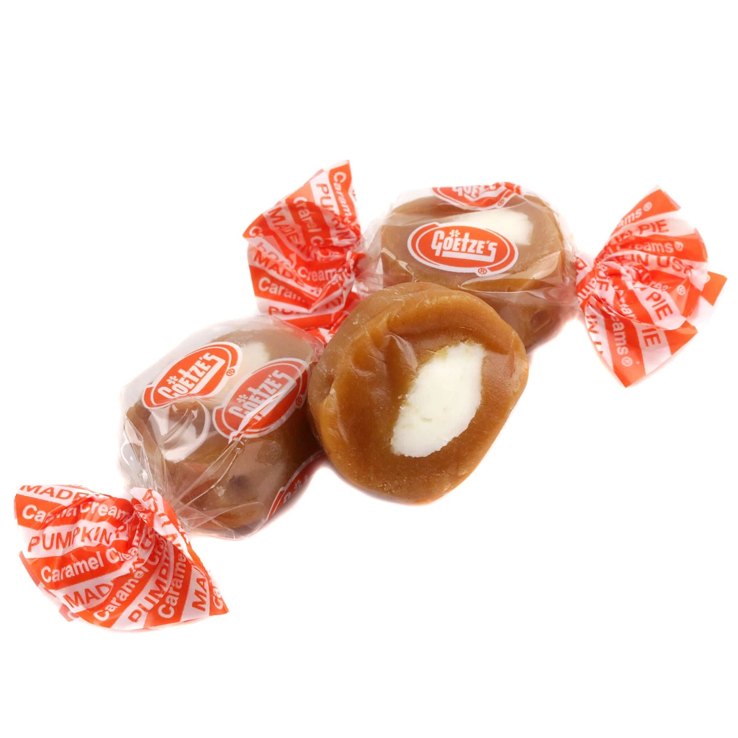 Four wrapped pumpkin caramels on a white background, with one candy unwrapped to show a smooth caramel center
