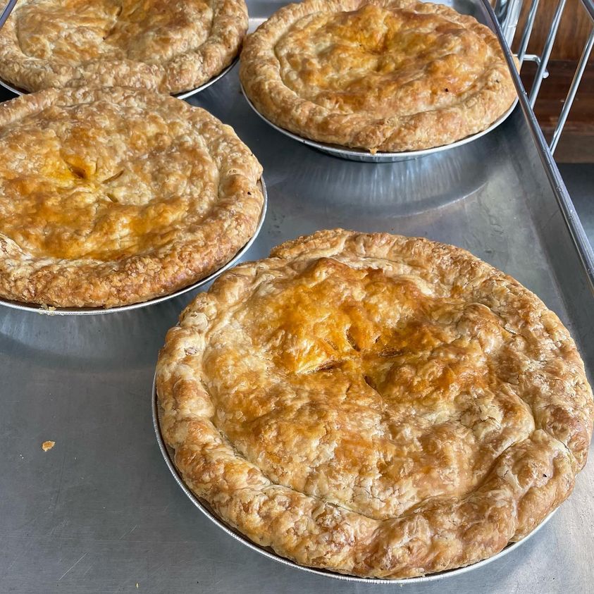 Overhead view of four Halloween Happy Apple Pies showcasing golden flaky crusts in metal tins on a baking tray