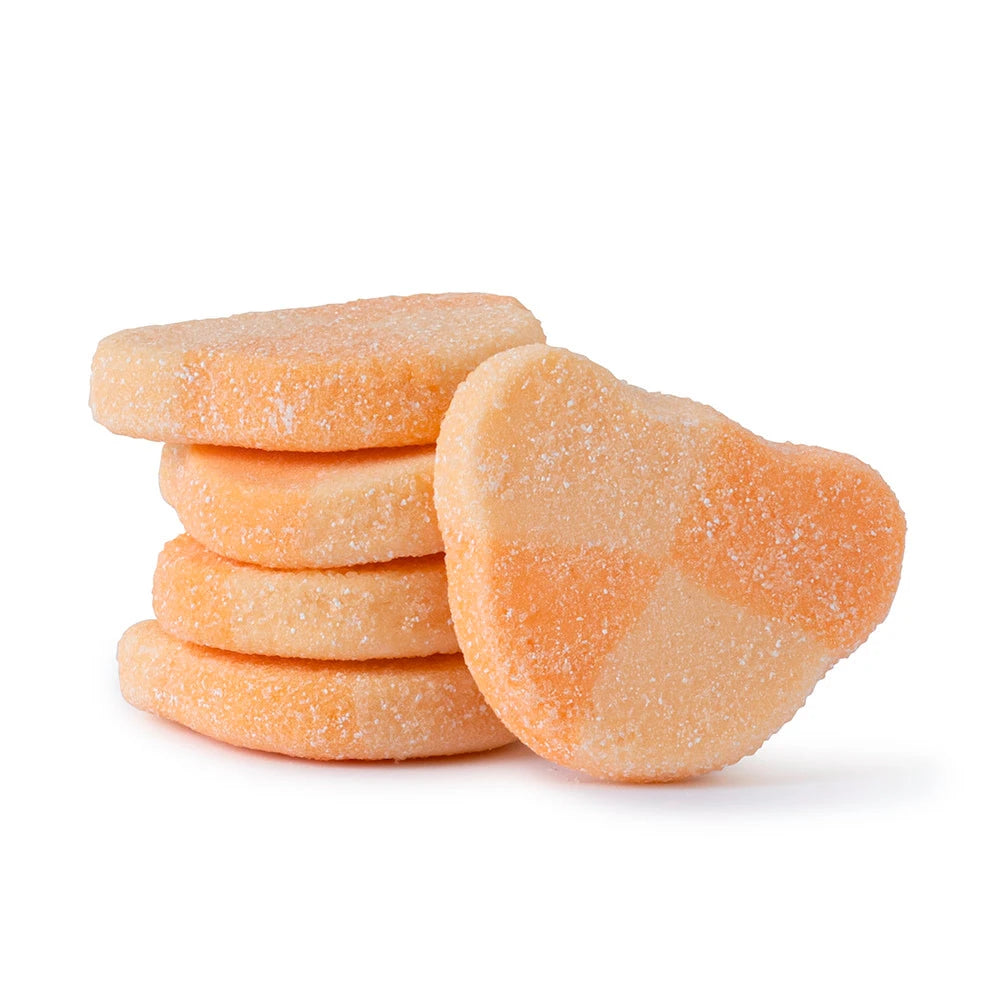 Stack of orange sour-coated gummy candies shaped like teddy bear heads on a white background